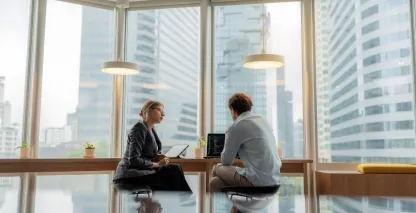Man and woman sitting by a window and looking at a computer screen