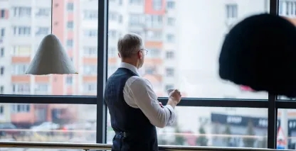 Man looking out the window in a high-rise building