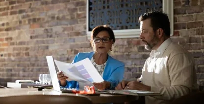 Business professionals reviewing documents and discussing information at a table with a laptop