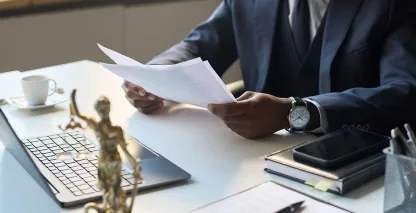 Legal professional reviewing documents at a desk with a laptop