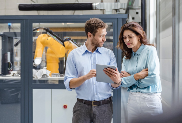 Two people in a factory looking at a computer tablet.