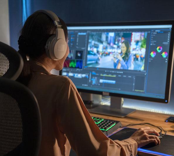 A woman editing video on a desktop computer