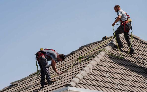 Two roofers working on a residential property.