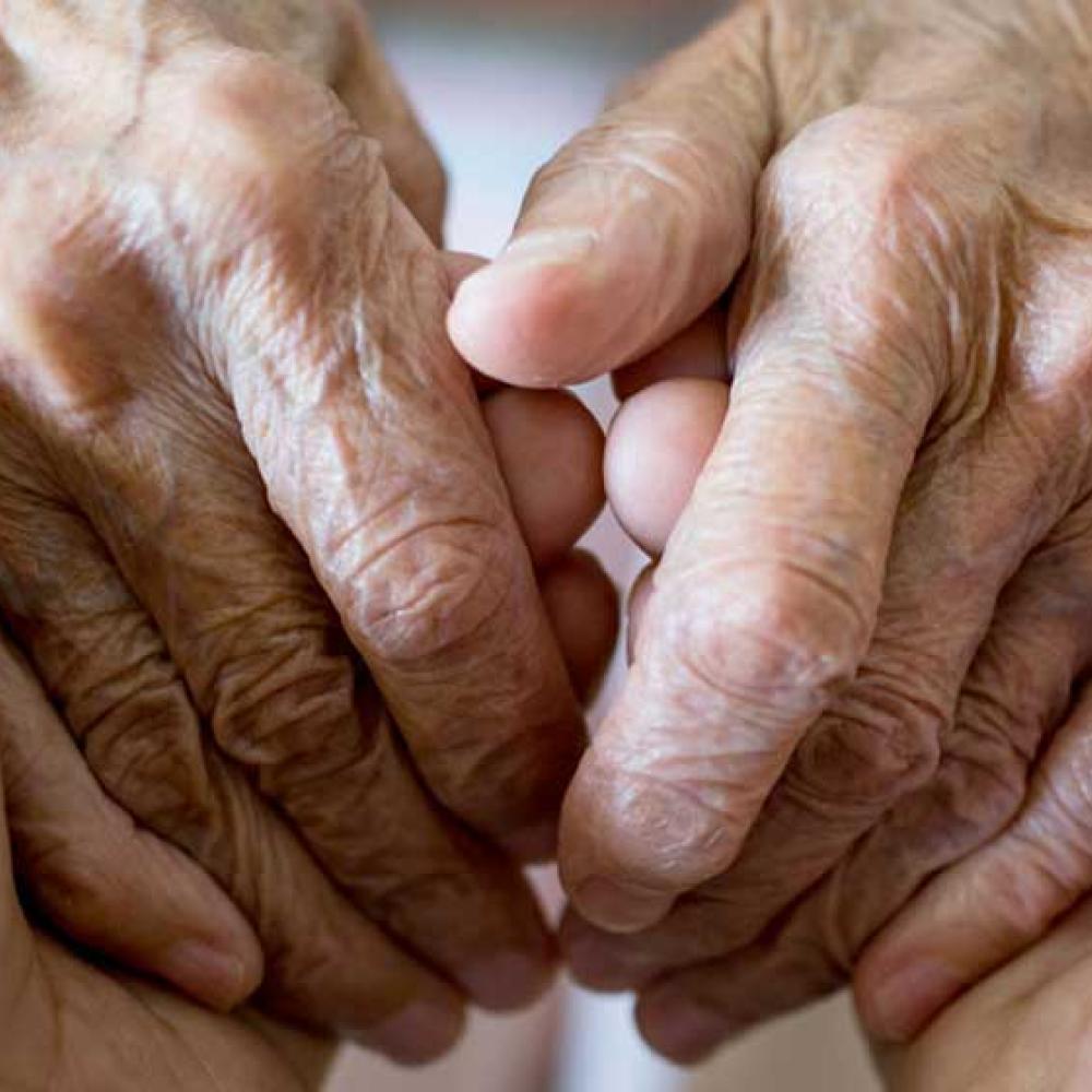 A caregiver holding hands with an elderly patient