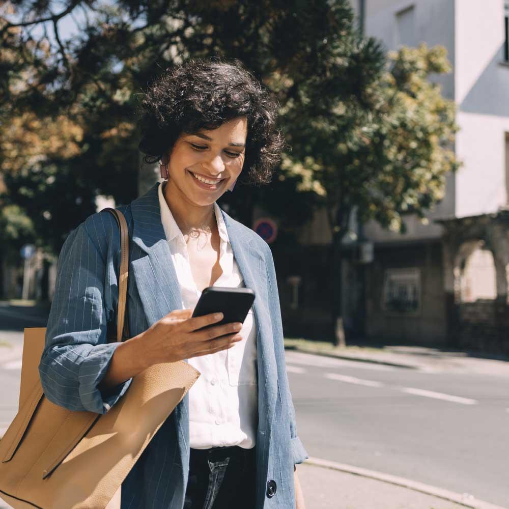 A woman walking outside while banking on her phone. 